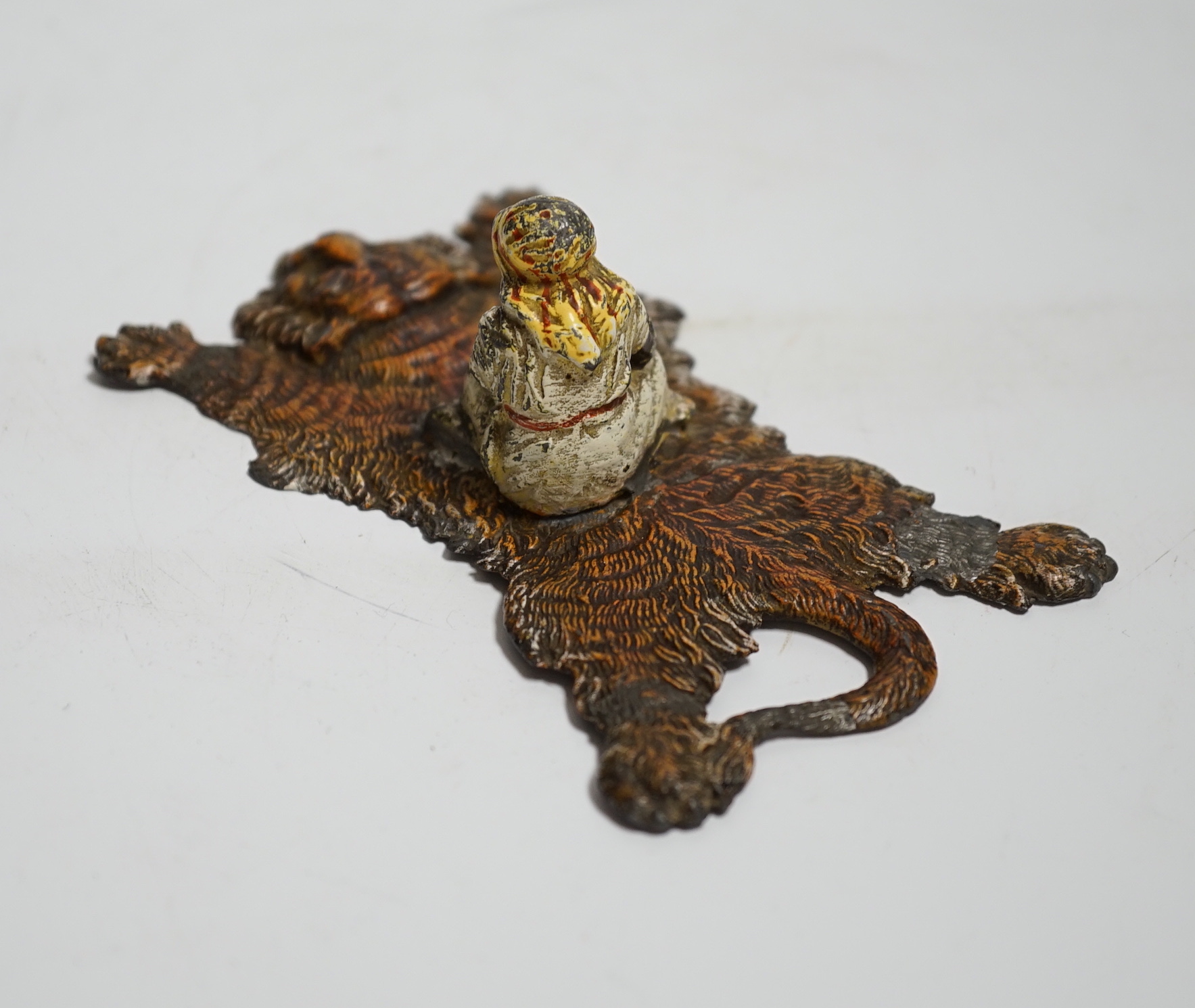 A Bergmann style painted lead figure of a gentleman on a tiger skin, 12.5cm long